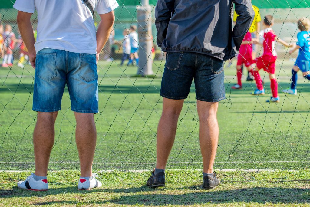 Pères regardant jouer leurs enfants au foot