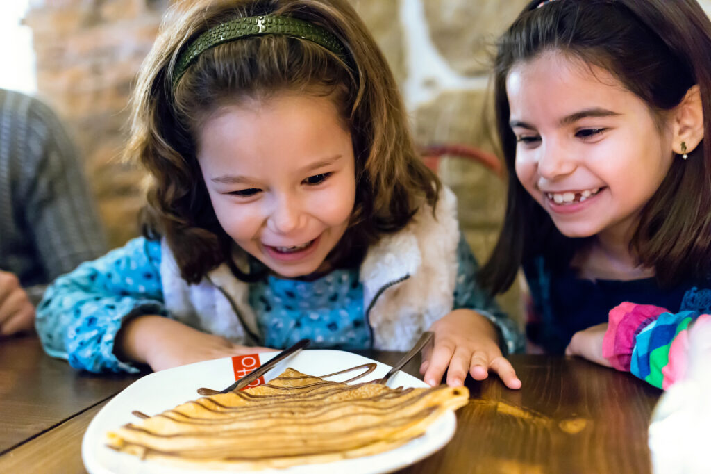 fillette mangeant une crêpe au restaurant